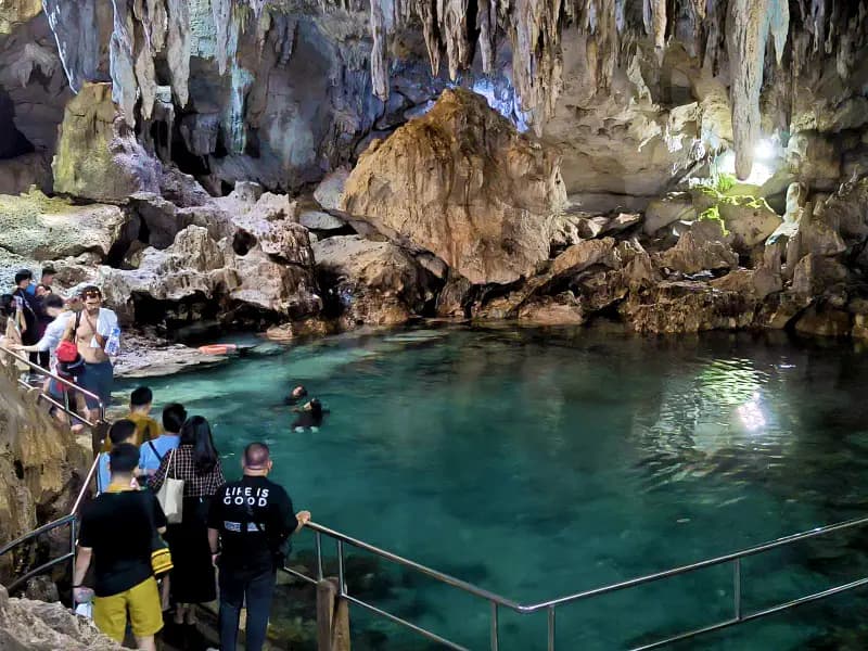 Visitors exploring the clear underground pool inside Hinagdanan Cave