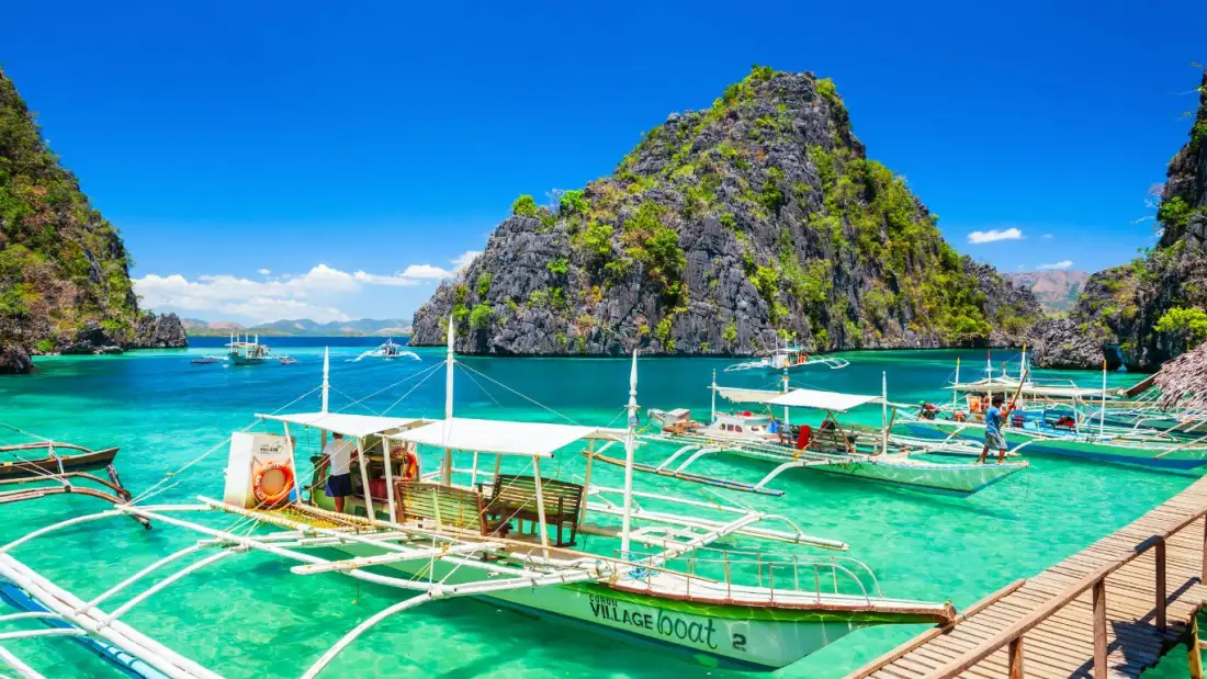 Traditional boats in a bright turquoise Philippine lagoon
