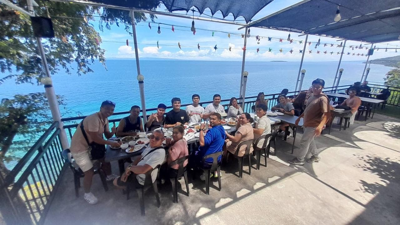Filipino corporate group enjoying a meal at an overlooking restaurant with scenic ocean views in Oslob, Cebu.