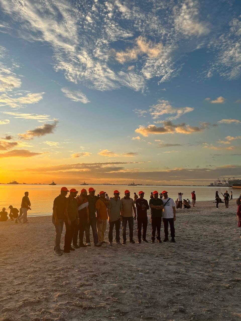 Group of doctors from Popular Pharmaceuticals posing at Manila Baywalk Dolomite Beach during a golden sunset in Manila, Philippines.